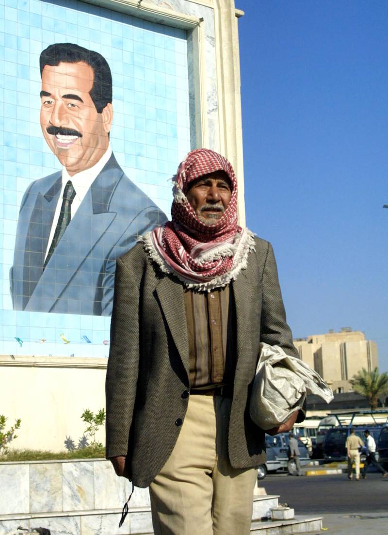 An Iraqi stands in front of a picture of Saddam Hussein in Baghdad, in November 2002.  AFP