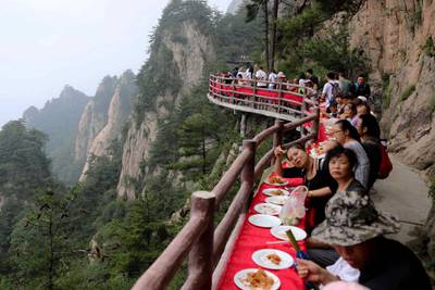 CORRECTION / This photo taken on July 8, 2018 shows tourists during a banquet held along the edge of a cliff, at Laojun Mountain in Luoyang in China's central Henan province. The banquet was held on a mountain cliff 2,000-metres (6,500-ft.) above sea level to attract tourists. - China OUT
 / AFP / -
