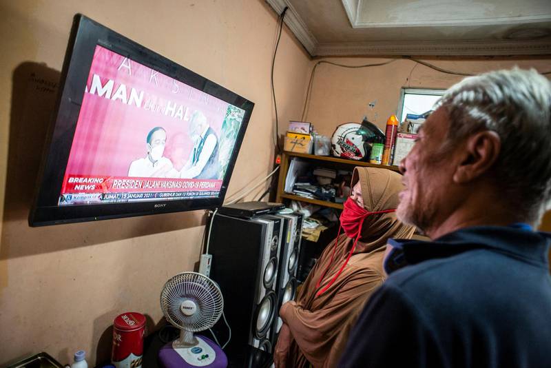 Indonesians watch a television showing live news of Indonesian President Joko Widodo receiving his Covid-19 vaccine shot in Jakarta, Indonesia. Reuters