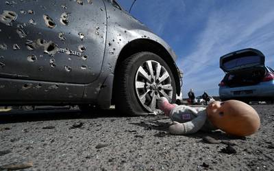 An abandoned doll next to a car riddled with bullets in Irpin, north of Kyiv. AFP