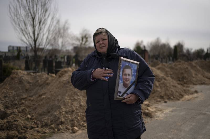A woman carries the portrait of Dmytro Stefienko, 32, a civilian killed during the war, during his funeral in Bucha, Ukraine. AP