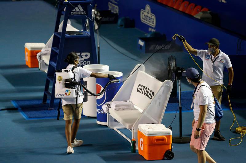 Workers spray disinfectant onto the players' benches, between second round matches at the Mexican Open tennis tournament in Acapulco. AP Photo