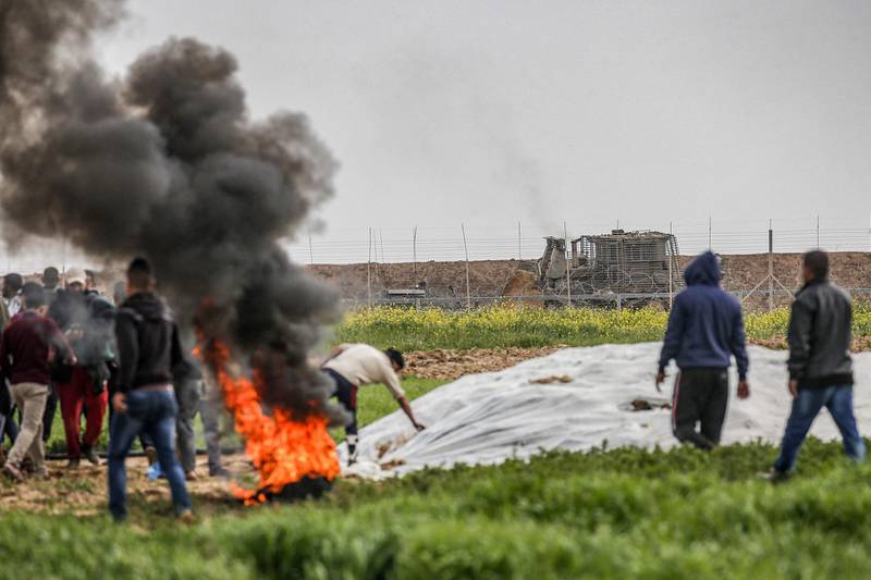 Palestinians set fire to tyres along the Gaza-Israel border east of Khan Yunis in the southern Gaza Strip. Israeli forces shot dead a Palestinian before extracting his body with a bulldozer.  AFP