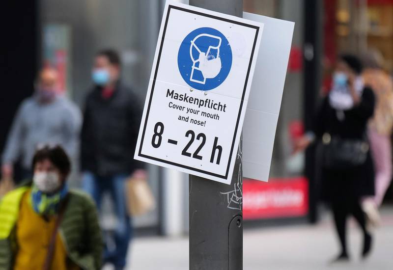 People walk past a sign reading "Mask is mandatory" on a shopping street in Frankfurt, Germany. Reuters