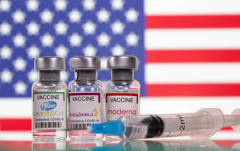 Vials with Pfizer-BioNTech, AstraZeneca, and Moderna coronavirus disease (COVID-19) vaccine labels are seen in front of a U.S. flag in this illustration picture taken March 19, 2021. REUTERS/Dado Ruvic/Illustration