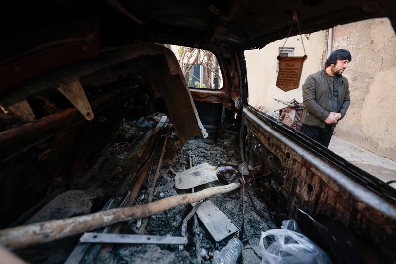 Ajmal Ahmadi stands beside a car which was damaged during a US drone strike that killed 10 civilians, including seven children, as he speaks with journalists at the house's courtyard in Kabul, Afghanistan, on November 7, 2021. Reuters
