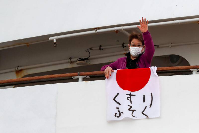 A woman waves after hanging a Japanese flag that reads "shortage of medicine" on the cruise ship Diamond Princess, where 10 more people were tested positive for coronavirus on Thursday, to the port as it is anchored at Daikoku Pier Cruise Terminal in Yokohama, south of Tokyo, Japan. Reuters