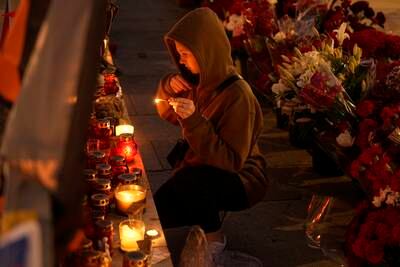 A young woman crosses herself as she lights a candle at an informal street memorial near the Kremlin, Moscow, for the Wagner Group members killed in the plane crash. AP
