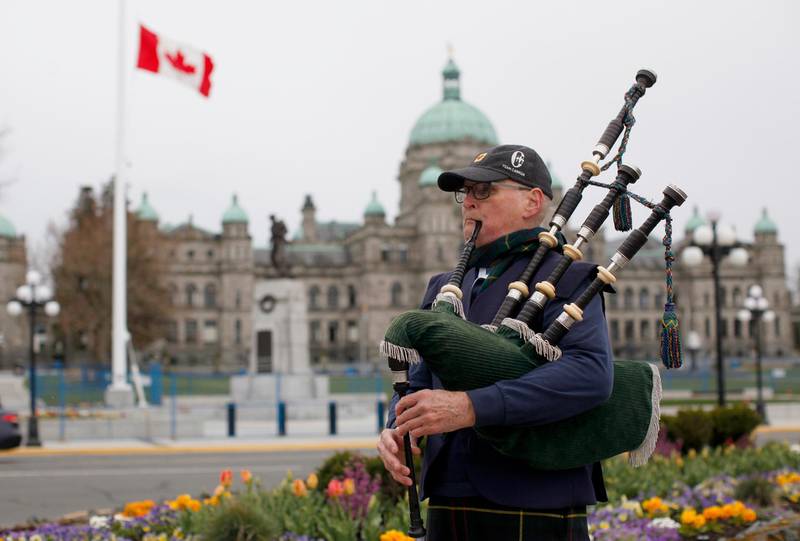 The British Columbia Legislature flies the Canadian flag at half-mast in Victoria, as piper Ken Wilson plays the 'Heights of Dargai'. AP Photo