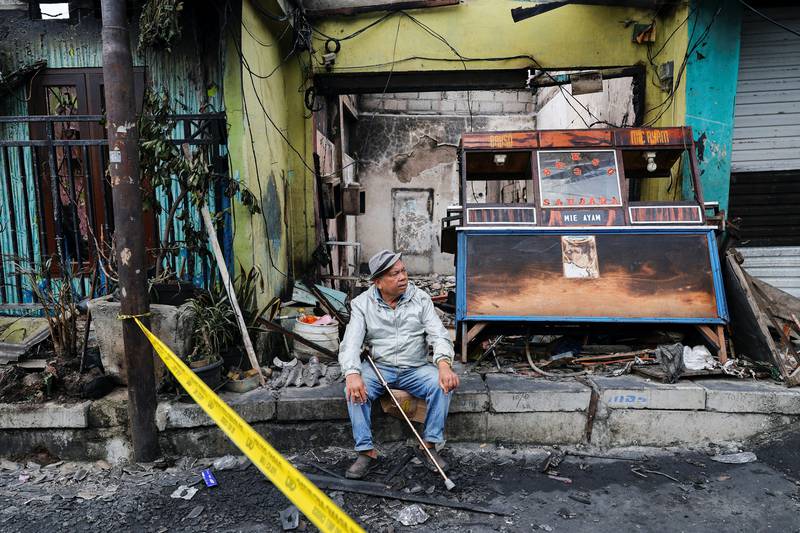 A resident sits outside a burnt stall near the site. The blaze began at 8pm on March 3. Reuters