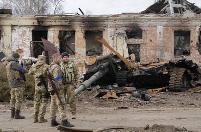 Ukrainian soldiers surrounded by debris from a Russian tank after fighting in Trostsyanets, 400km east of the capital Kyiv. AP