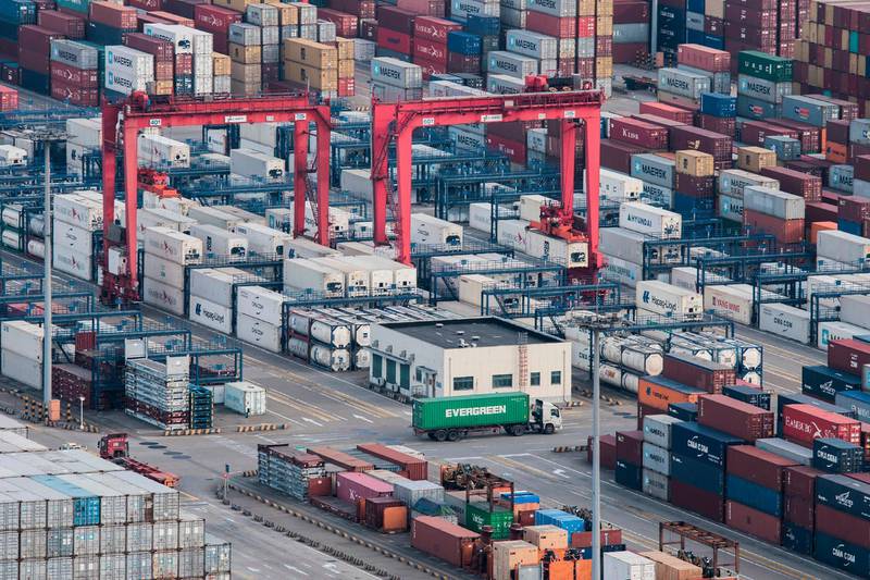 FILE - In this March 29, 2018, file photo, a cargo truck drives amid stacked shipping containers at the Yangshan port in Shanghai. China's export growth sank in November, 2018, as global demand weakened, adding to pressure on Beijing ahead of trade talks with Washington. (AP Photo/File)