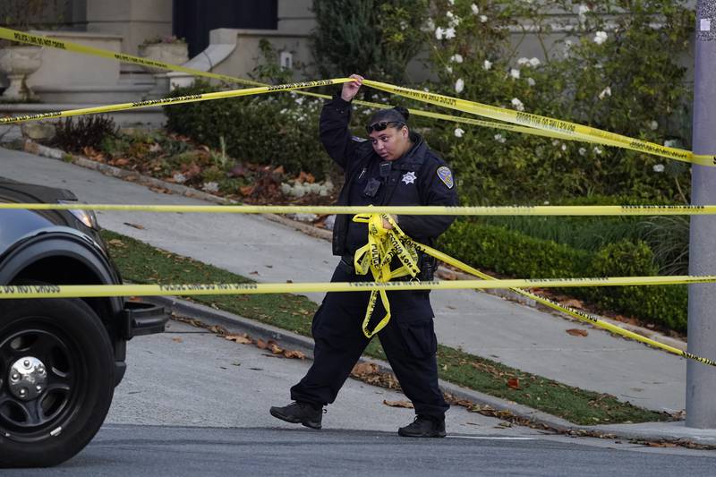 A police officer rolls out yellow tape near the Pelosi residence. The attack on Mr Pelosi comes before the US midterms and is the latest violence against a political figure. AP
