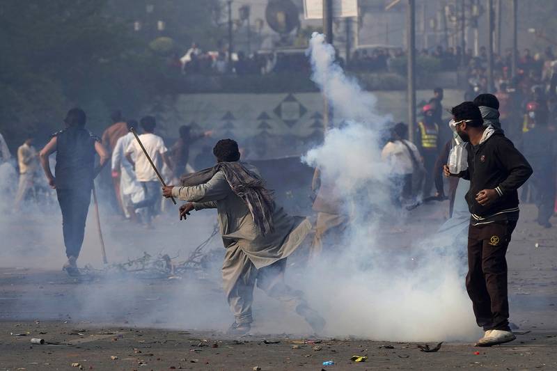 A supporter of former Prime Minister Imran Khan hurls back a tear gas shell fired by riot police during clashes in Lahore on Wednesday, March 15, 2023. AP