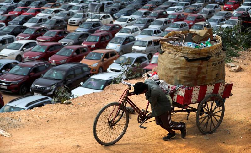 A ragpicker pushes his tricycle as Christians sit in their vehicles maintaining social distancing during a drive-in mass at Bethel AG Church in Bengaluru, India. AP Photo