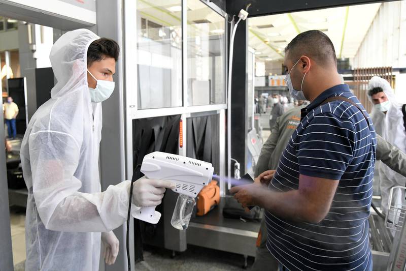 A health worker sprays sanitizer on a passenger at Damascus International Airport on its re-opening day for regular international commercial traffic. Reuters