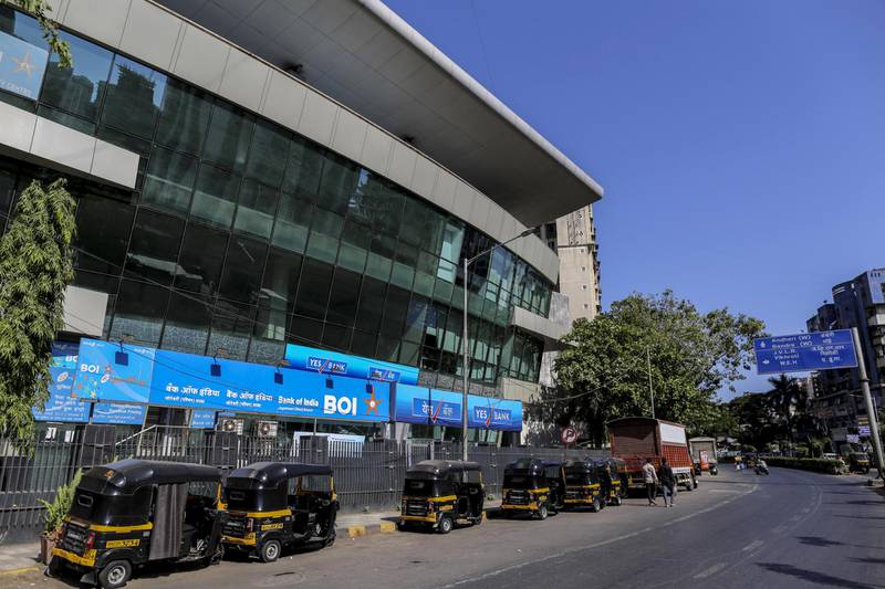 Auto-rickshaws sit parked outside branches of Bank of India and Yes Bank Ltd. on a near-empty street in Mumbai, India. Bloomberg