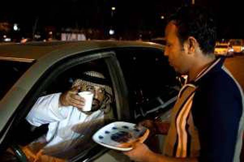 18/12/2009 - Abu Dhabi, UAE -  Ahmed Ali Alyfei has tea delivered to his car after beeping his horn in Al Reehan, Abu Dhabi on Friday December 18, 2009. 
 (Andrew Henderson / The National)
