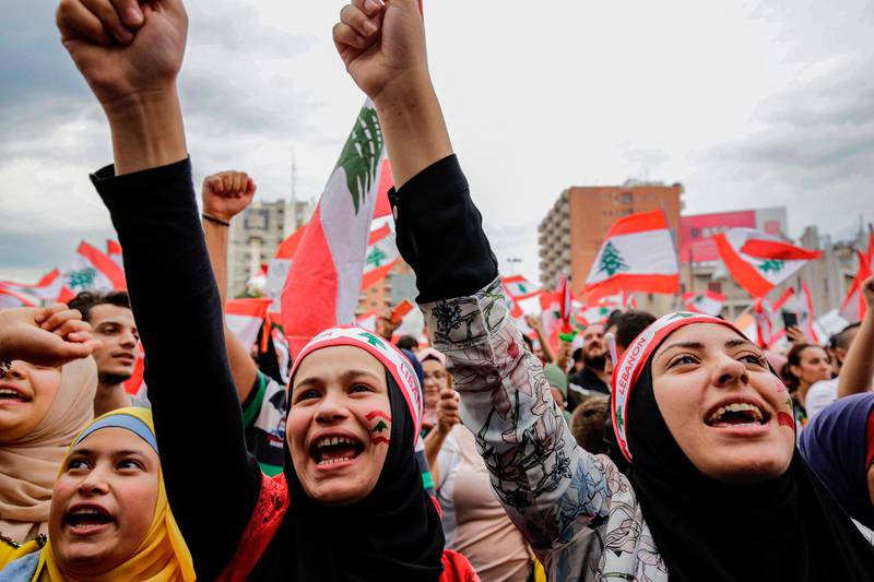 Women wearing bandanas showing the Lebanese national flag chant slogans during a demonstration in the northern city of Tripoli's al-Nour Square on October 23, 2019, on the seventh day of protest against tax increases and official corruption. The northern seaside city of Tripoli, once perceived as a hotbed for insurgents, has emerged as the scene of Lebanon's most festive protests, with euphoric crowds dancing deep into the night. For days, hundreds of demonstrators denouncing dire living conditions, corruption and tax hikes, have converged on Tripoli's Al-Nour Square, with focused protests evolving into an impromptu concert after the sun sets.  / AFP / Ibrahim CHALHOUB
