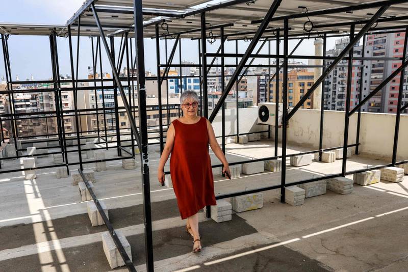 Lebanese homemaker Zeina Sayegh walks beneath the solar panels she installed atop her apartment building in Lebanon's capital Beirut.  