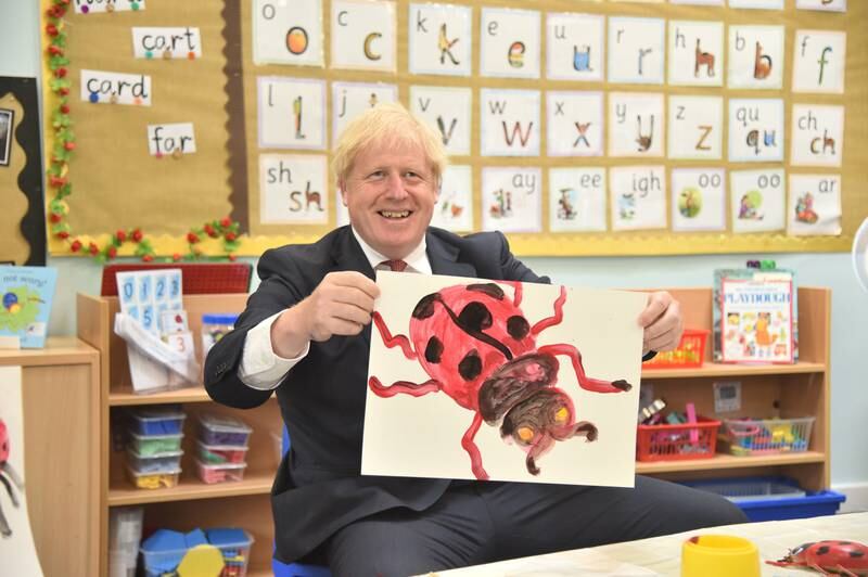 Mr Johnson holds a painting of a ladybird during a visit to The Discovery School in West Malling, in July 2020. Getty Images
