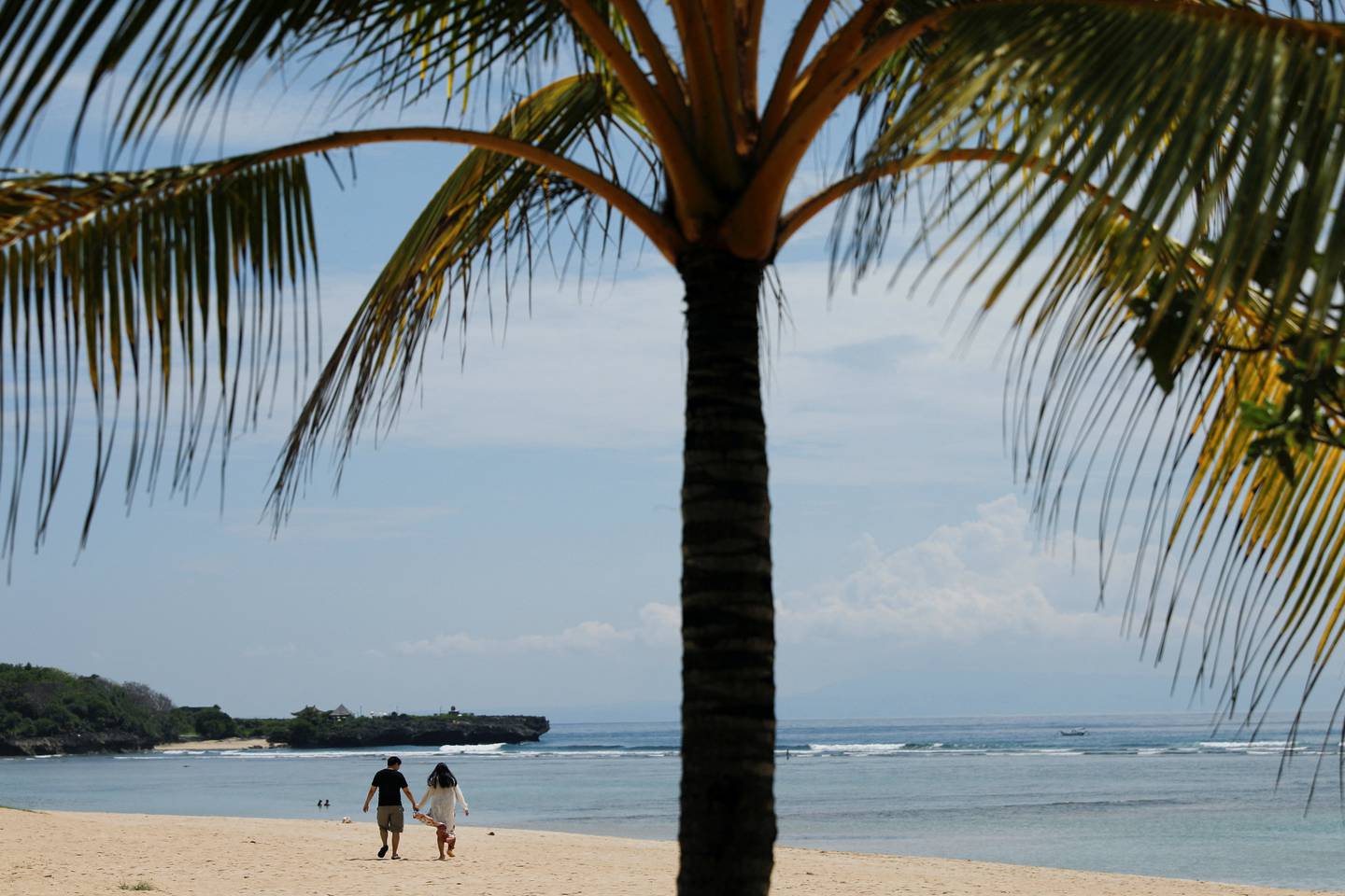 A couple walk along the beach in Nusa Dua, Bali. It is hoped the G20 summit will help persuade tourists to return to the island. Reuters