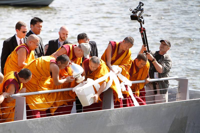 The Dalai Lama, center left in baseball cap, pours mandala sand mixed with river water into the Anacostia River as part of a blessing ceremony Saturday, July 16, 2011, in Washington. President Barack Obama held a White House meeting Saturday with the Dalai Lama, a fellow Nobel Peace Prize laureate, hours after China called on the U.S. to rescind an invitation that could sour relations with Beijing. (AP Photo/Jacquelyn Martin) *** Local Caption ***  Dalai Lama.JPEG-0da0e.jpg
