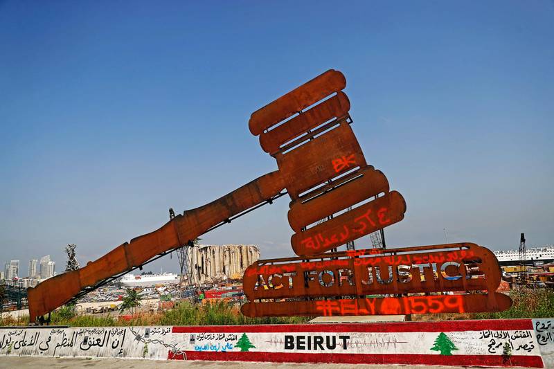 A gavel monument symbolising justice can be seen in front of the damaged grain silos at Beirut port, as Lebanon marks a year since an explosion ravaged the country's capital.