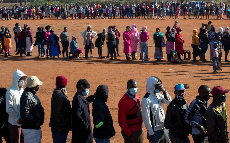 People affected by the coronavirus line up to receive food donations near Laudium, southwest of Pretoria, South Africa. AP Photo