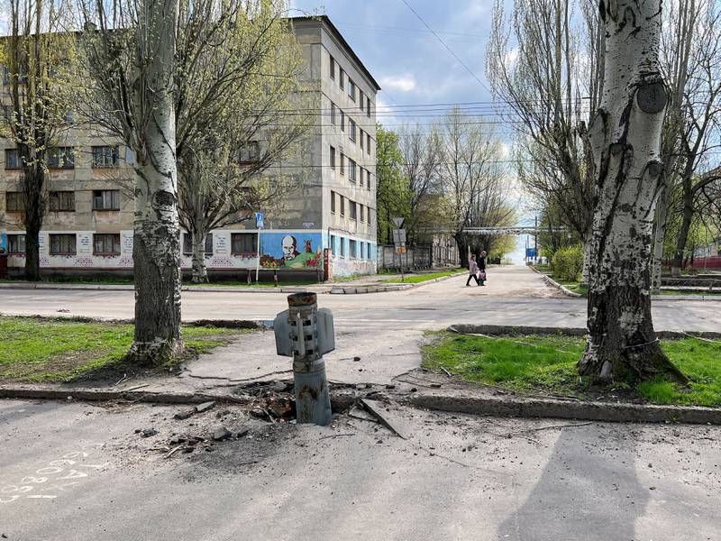 People walk along a street past a missile that stuck in the ground, amid Russia's invasion of Ukraine, in Rubizhne, Luhansk region, Ukraine. Reuters
