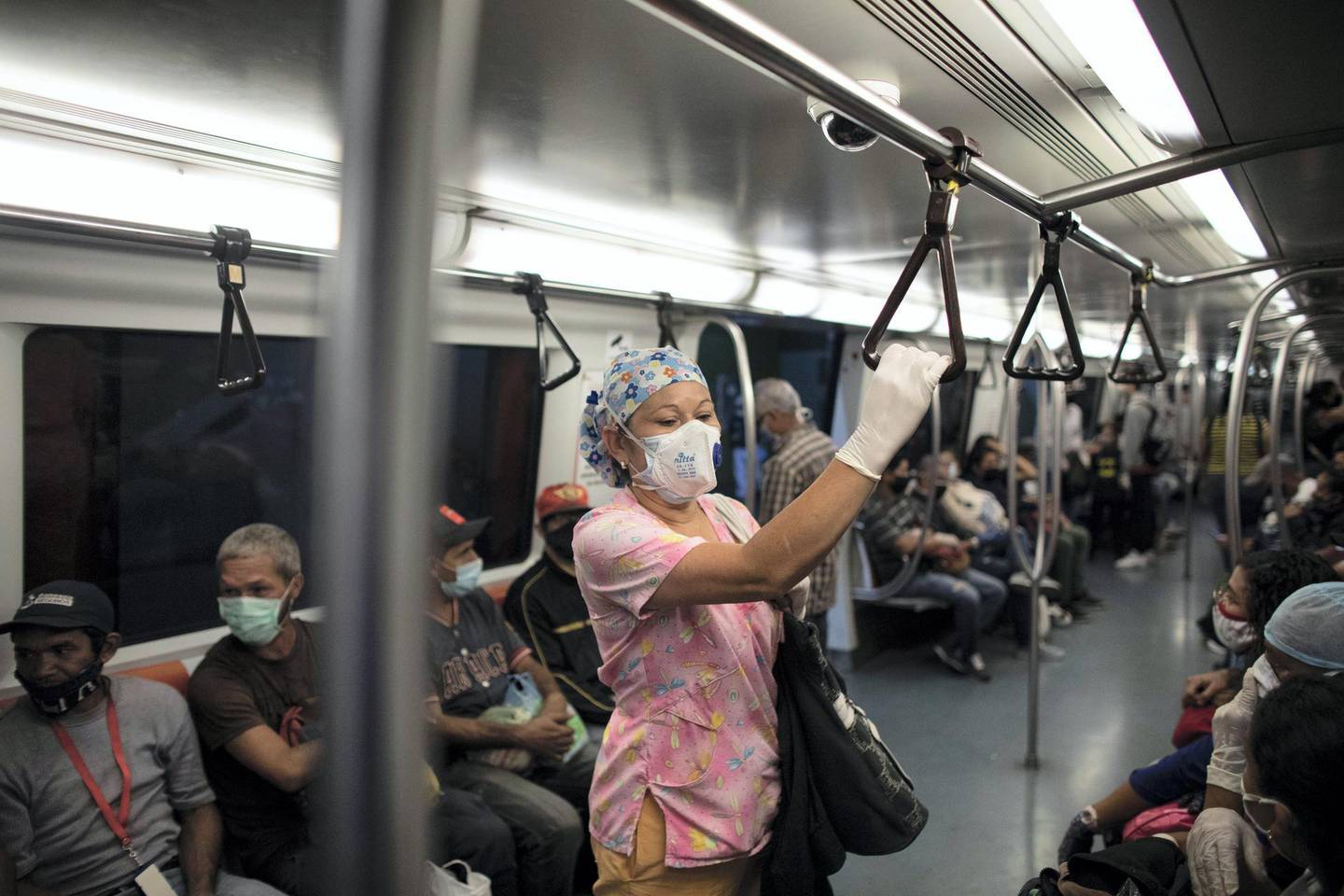 CARACAS, VENEZUELA - JUNE 26: Nurse Rosaura Rodriguez wearing a double mask and medical gloves, travels inside the subway to go home after work during week 17 of strict quarantine on June 26, 2020 in Caracas, Venezuela. Venezuelan nurse Rosaura Rodriguez has worked in public health institutions for 17 years. Since the beginning of the COVID-19 outbreak, she works seven days a week for minimum wage (4USD). Rodriguez wakes up every day at 3:30 AM, and then has a two hour commute from her house in the Petare slum to the health center Alcides Rodriguez. She takes care of patients with symptoms of COVID-19 and says most people do not understand the real danger of the pandemic. Back home, she undergoes daily disinfection rituals to protect her son and grandson, who live with her. As most people in Caracas, she suffers running water shortage and has to fill buckets in a public tap. Social and economic crisis in the country do not help and people must go out to work or to get drinking water, unable to obey the obligatory isolation ordered by Maduro's government. (Photo by Leonardo Fernandez Viloria/Getty Images)