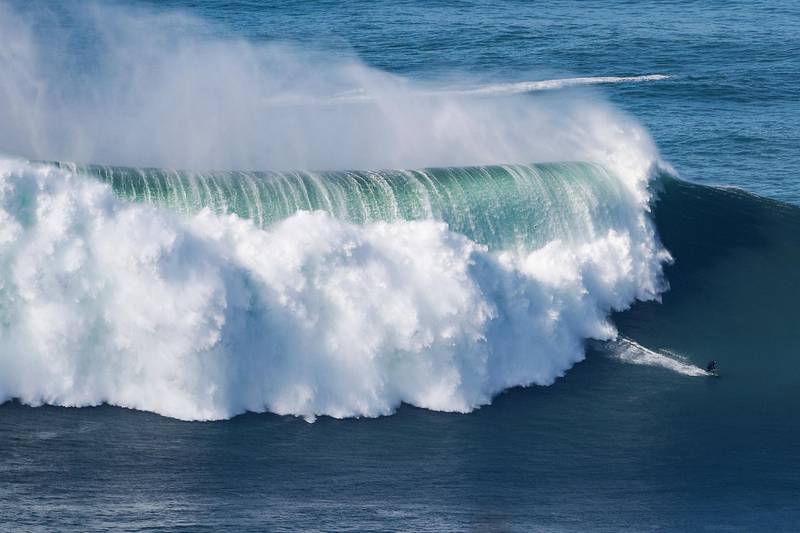 A surfer rides a wave amid a giant swell at Praia do Norte in Nazare on Thursday, October 29, 2020. AFP