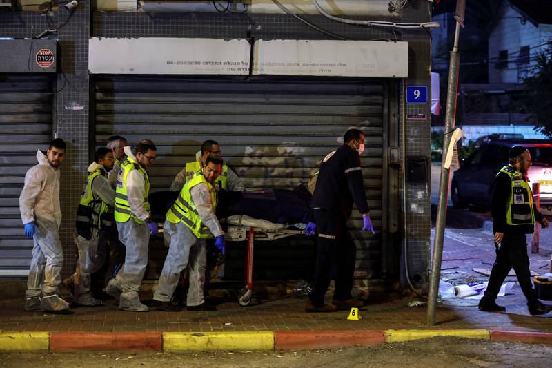 Israeli medical personnel and rescue workers evacuate a dead body from the scene of an attack in which people were killed by gunmen on a main street in Hadera. Reuters