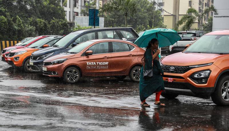 epa07753152 A woman walks past cars parked outside the Tata Motors showroom on Mira road in Mumbai, India, 02 August 2019. According to reports, auto industry sales are at their lowest level in almost two decades.  EPA/DIVYAKANT SOLANKI