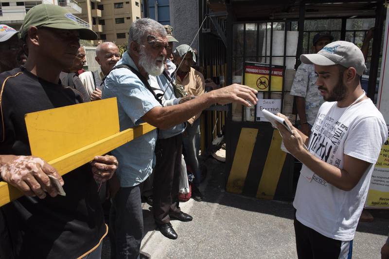 People wait for free soup outside a church in Caracas, Venezuela, on Saturday, Aug. 18, 2018. Venezuelan shops shuttered and lines formed at gas stations on Saturday as confusion reigned following measures announced by President Nicolas Maduro aimed at fighting an historic economic crisis in the oil-exporting nation. Photographer: Carlos Becerra/Bloomberg