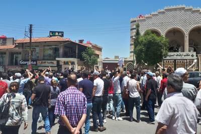 A handout picture released by the local news site Suwayda 24 shows Syrians chanting anti-government slogans as they protest the country's deteriorating economic conditions and corruption, in the southern city of Suwaida on June 9, 2020. 