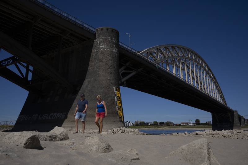 People take a stroll on the river bed of the Waal as water levels dropped because of drought in Nijmegen, Netherlands. AP