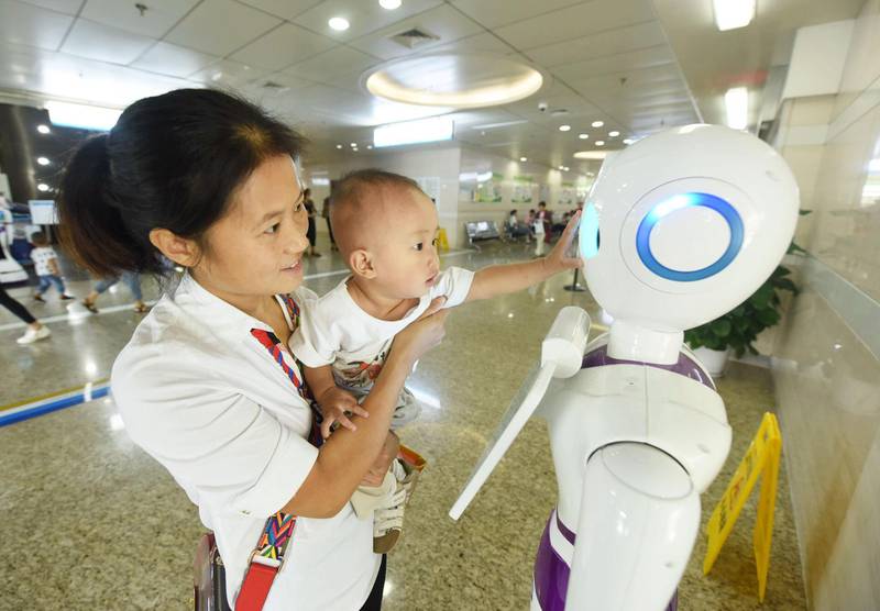 A child touches robot Xiaoyi that provides services such as giving directions and answering questions, at a hospital in Hangzhou in China's eastern Zhejiang province. AFP