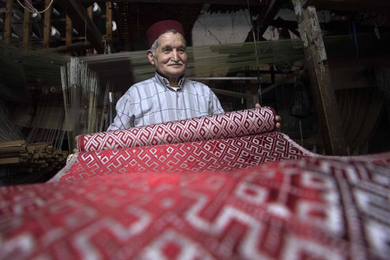 Abdelkader Ouazzani, the last of Morocco's brocade master weavers, displays tapestry at his workshop in the old city of Fes on April 10, 2019. His skillfull hands intricately create shimmering silk fabrics, enhanced with gold or silver thread, for bridal jewellery, designer creations or high-end furnishings. / AFP / FADEL SENNA
