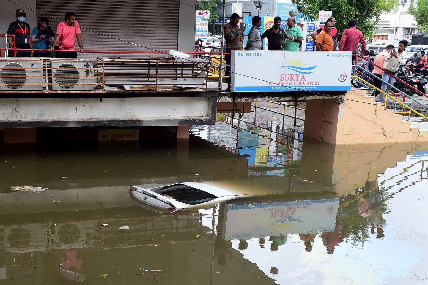 People look at a submerged car in a flooded commercial complex after heavy rains in Ahmedabad on July 11.  AFP