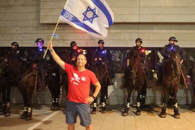 A protester waves the flag of Israel in front of mounted police during the rally. AFP
