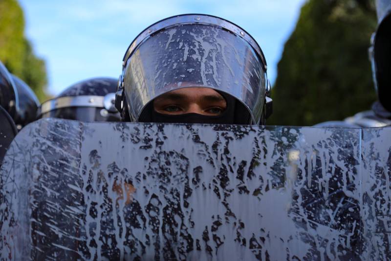 A Tunisian police officer's shield and helmet are covered with a liquid sprayed by protesters. AFP