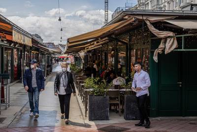 A restaurant worker waits for customers alongside an outdoor dining area in the Naschmarkt in Vienna, Austria. Bloomberg