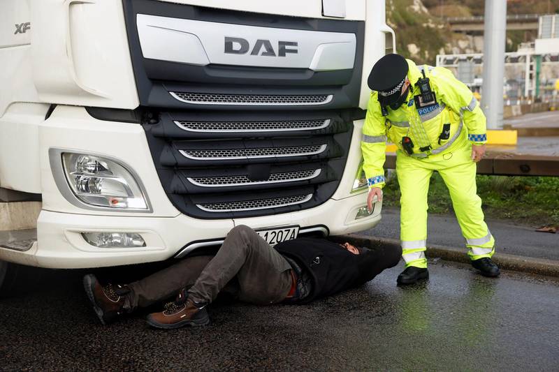 A person lies down in front of a lorry to stop it from leaving the Port of Dover, as EU countries impose a travel ban from the UK following the coronavirus disease (COVID-19) outbreak, in Dover, Britain, December 23, 2020. REUTERS/John Sibley