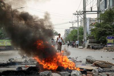A demonstrator looks on along burning debris during a protest against the military coup in Mandalay. EPA