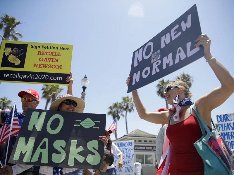 Demonstrators hold signs as they protest the lockdown and wearing masks in California, US. Marcio Jose Sanchez / AP