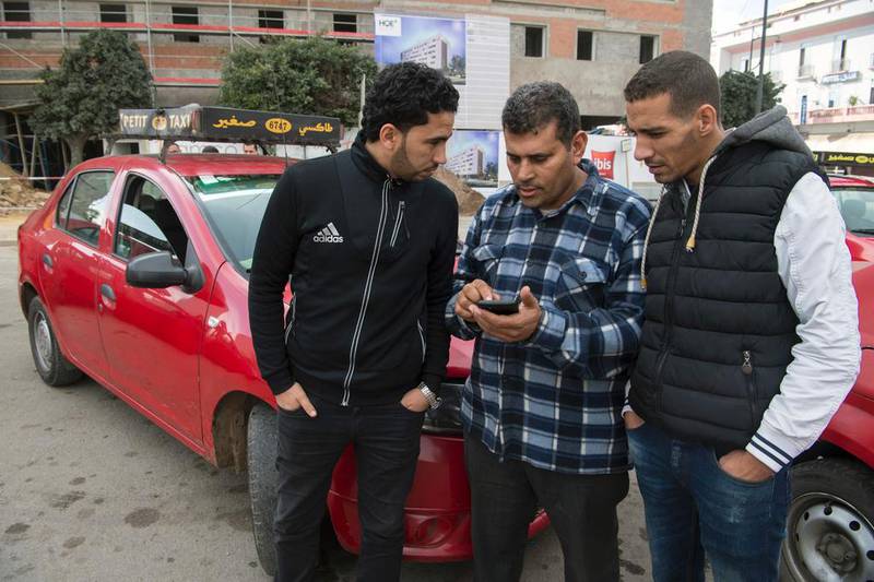 Moroccan taxi drivers check the Uber app as they wait for customers in Casablanca on January 6, 2017. In Casablanca taxi drivers are at war with Uber, demanding the government take action against the American company. Fadel Senna/AFP