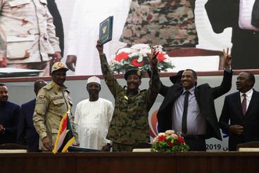 Sudan's protest leader Ahmad Rabie, flashes the victory gesture alongside General Abdel Fattah Al Burhan, the chief of Sudan's ruling Transitional Military Council, during a ceremony where they signed a "constitutional declaration" that paves the way for a transition to civilian rule. AFP 