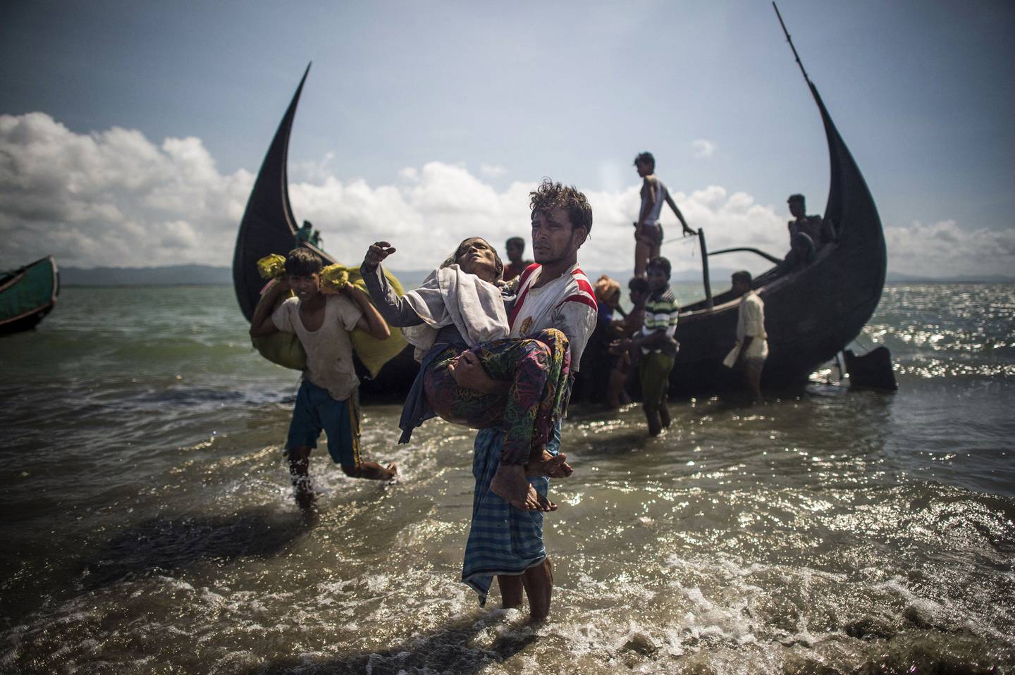 Un homme bangladais aide des réfugiés musulmans rohingyas à débarquer d'un bateau sur la rive bangladaise de la rivière Naf.  AFP