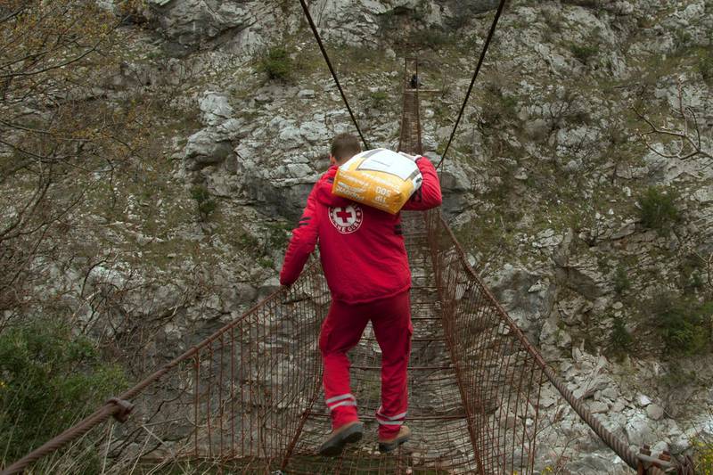 A Montenegrian Red Cross volunteer carries a bag of flour over a suspension bridge in the village of Dromira, 25km north of Podgorica, as Montenegro remains on lockdown.  Reuters
